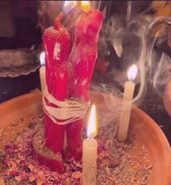 velas rojas en formas de hombre y mujer amarradas y velas blancas encendida alrededor en un plato de arcilla amarre de amor